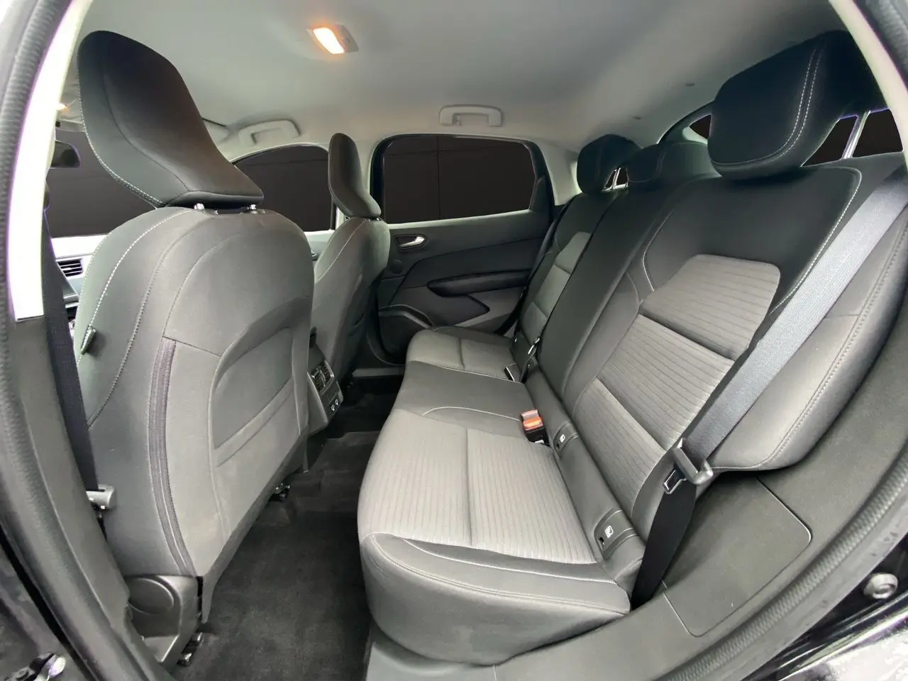 Vue intérieure côté droit des sièges arrière noirs du Renault Arkana 2024, avec ceintures et appuie-têtes visibles.