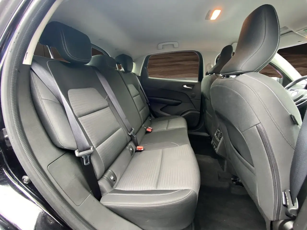 Vue intérieure arrière côté gauche du Renault Arkana noir 2024, montrant les sièges arrière en tissu et cuir.