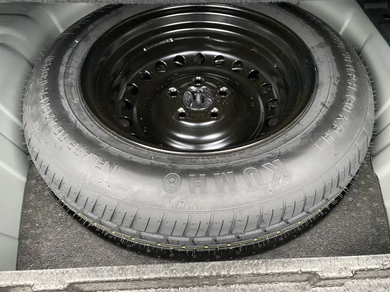 Gros plan sur la roue de secours noire en acier du Renault Arkana TCE 140 Essence 2024, logée dans le coffre.