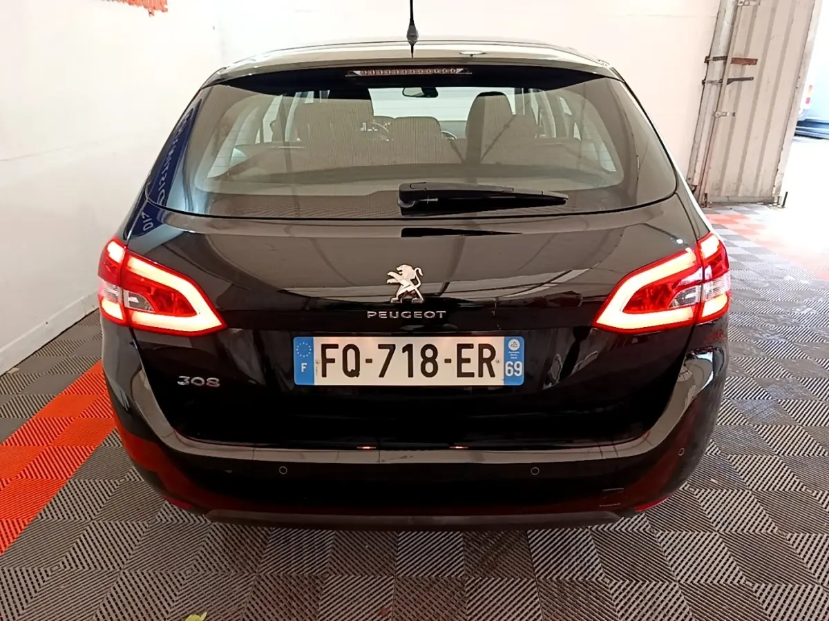 Vue arrière d'une Peugeot 308 noire de 2020 avec feux arrière allumés dans un garage fermé.