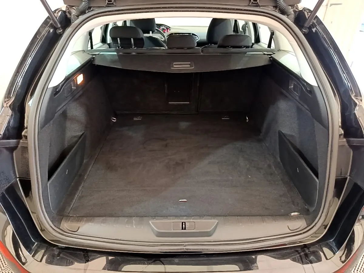 Coffre ouvert d’une Peugeot 308 noire, vue arrière montrant l’espace de chargement et la banquette arrière.