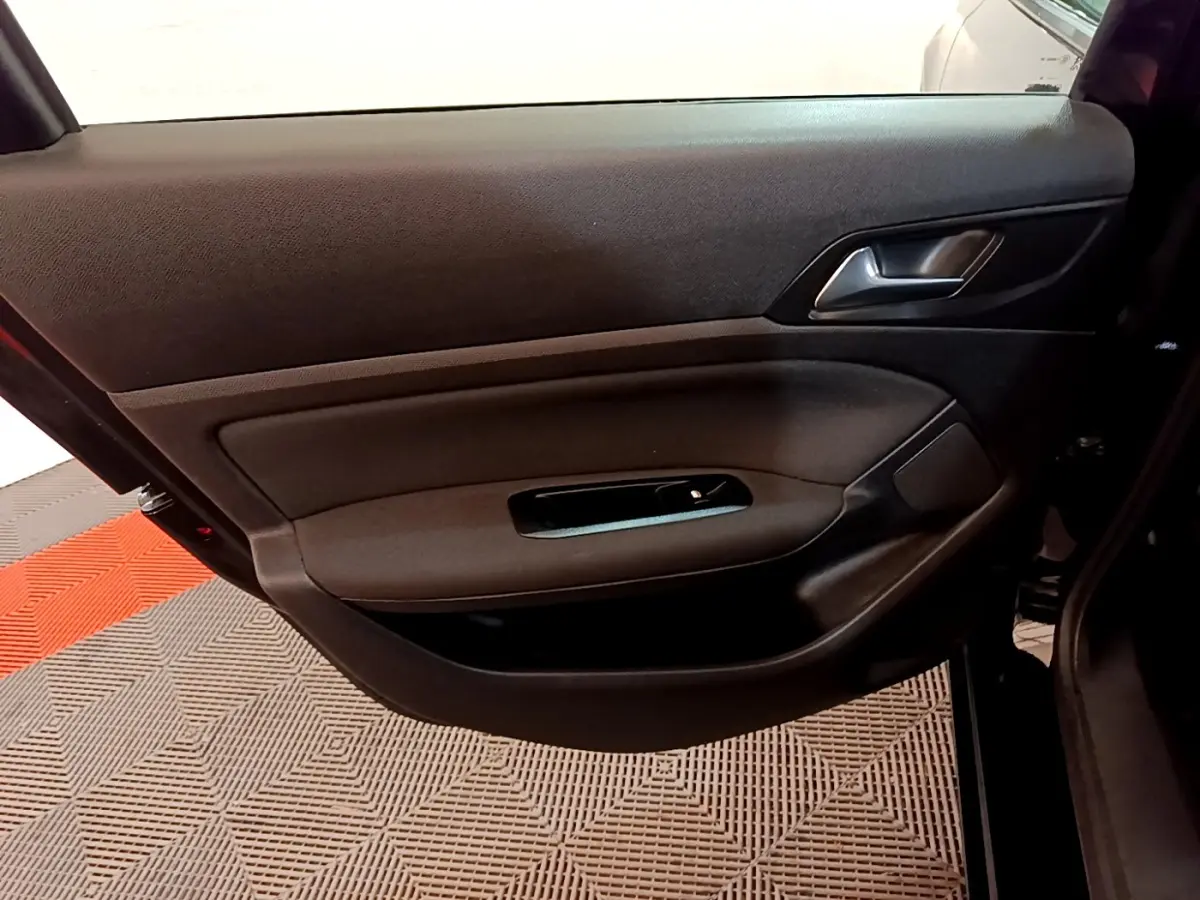 Vue intérieure de la porte avant gauche noire d'une Peugeot 308 2020, avec poignée et commande de vitre visible.