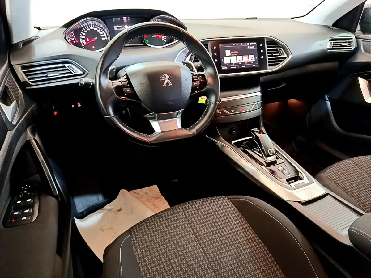 Intérieur noir de la Peugeot 308 2020, vue côté conducteur montrant volant cuir, tableau de bord digital et écran tactile central.