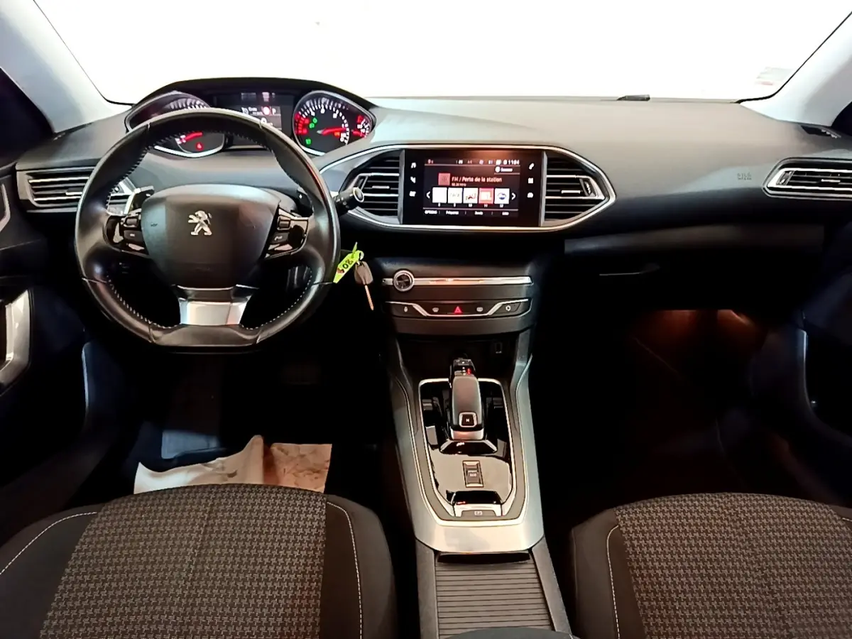 Intérieur de Peugeot 308 2020 vue de face, tableau de bord noir avec écran tactile central et volant cuir multifonctions.