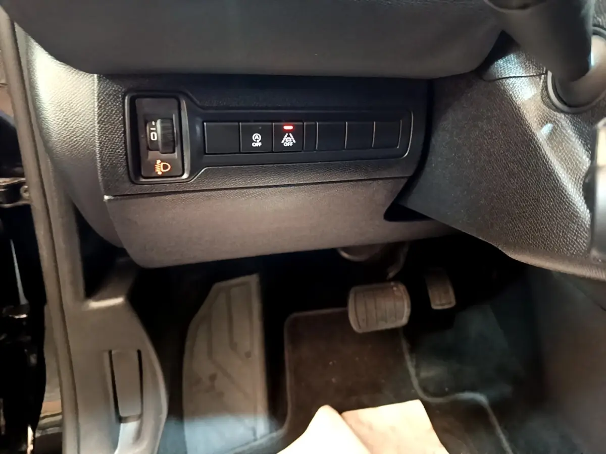 Vue intérieure côté conducteur de la Peugeot 308 noire, montrant les commandes d'éclairage et pédales au plancher.