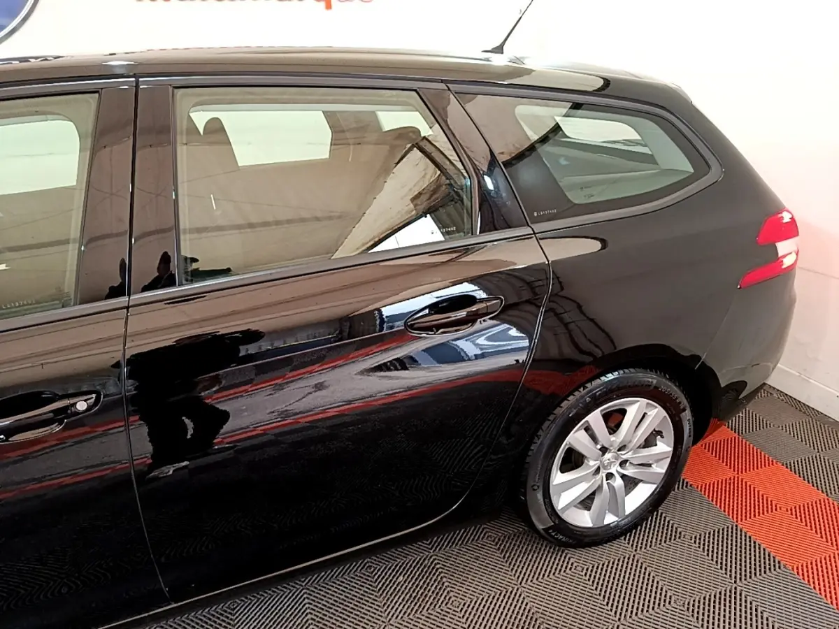 Vue latérale côté droit d'une Peugeot 308 noire de 2020, mettant en valeur les jantes alliage et la carrosserie brillante.