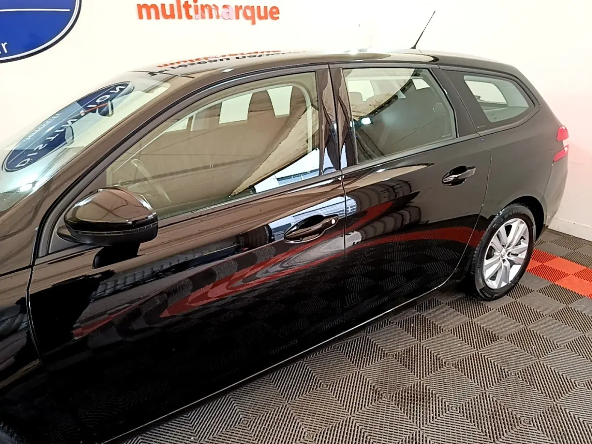 Profil côté gauche d'une Peugeot 308 noire 2020 en version break, avec jantes argentées et rétroviseur noir brillant.