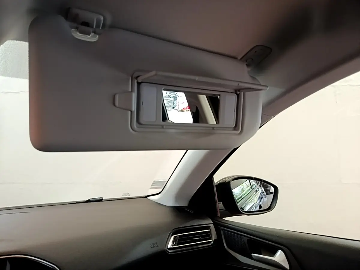 Intérieur de la Peugeot 308 noir, vue côté passager avec pare-soleil relevé et rétroviseur extérieur visible.
