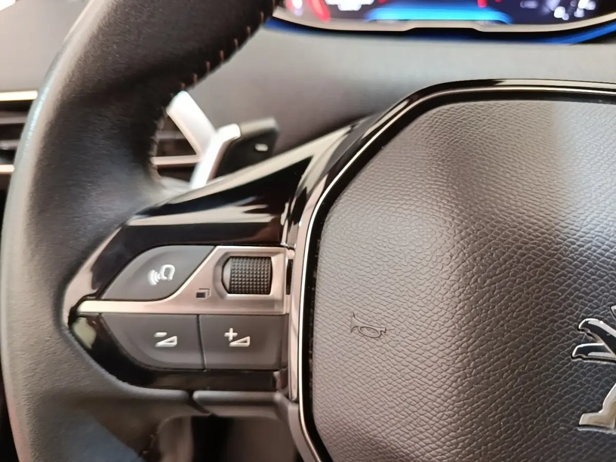 Gros plan sur le volant cuir noir de la Peugeot 3008 2022 avec commandes multifonctions à gauche.