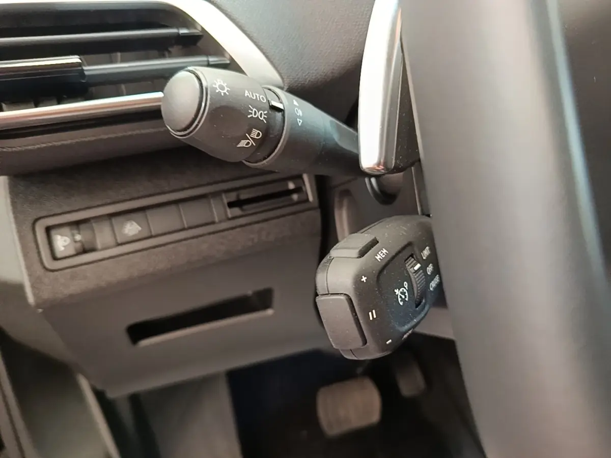 Gros plan sur les commandes du volant côté gauche du Peugeot 3008 noir, avec réglages phares et régulateur de vitesse.