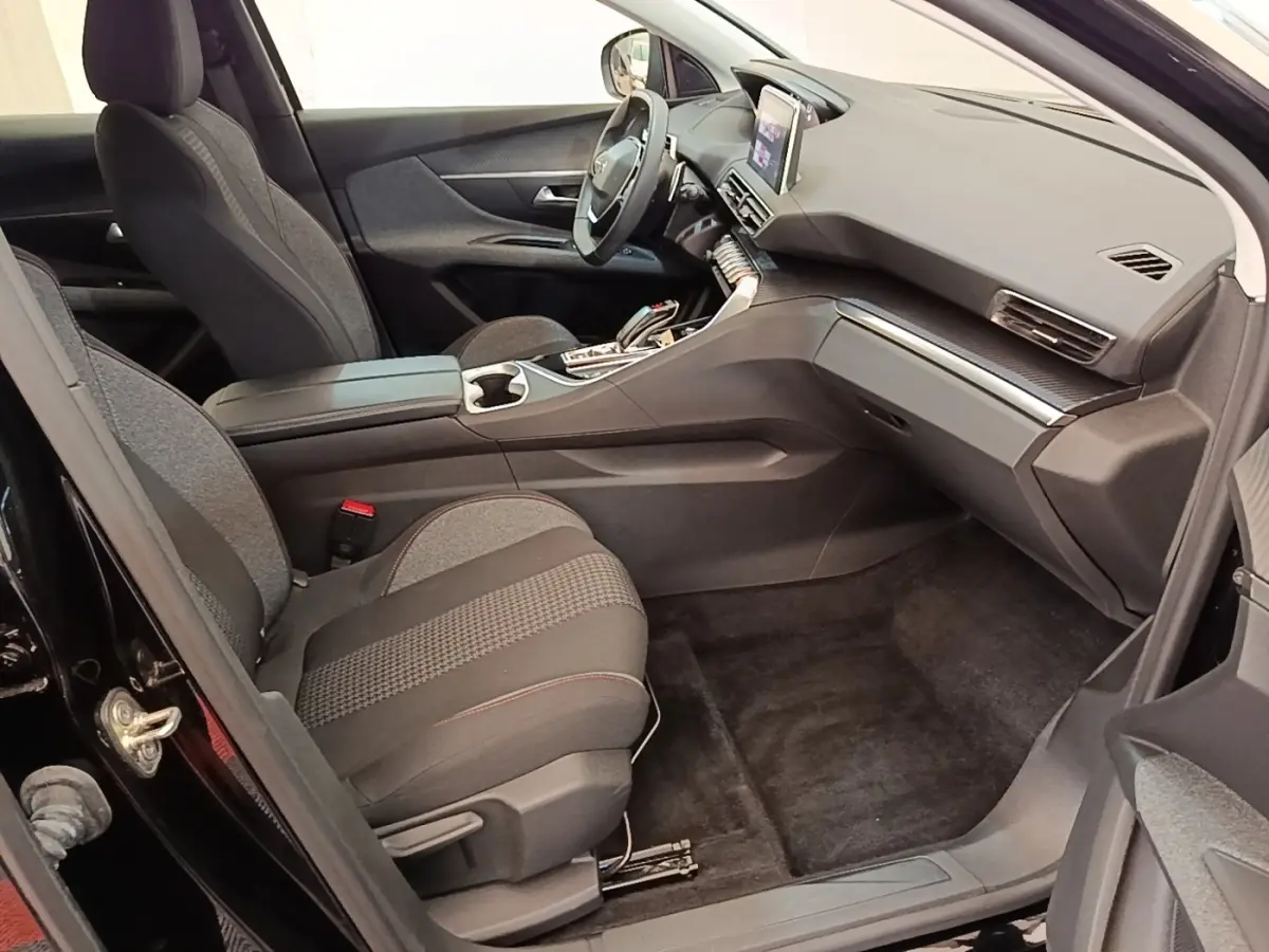 Vue intérieure côté passager avant du Peugeot 3008 noir 2022, avec tableau de bord moderne et sièges tissu gris.