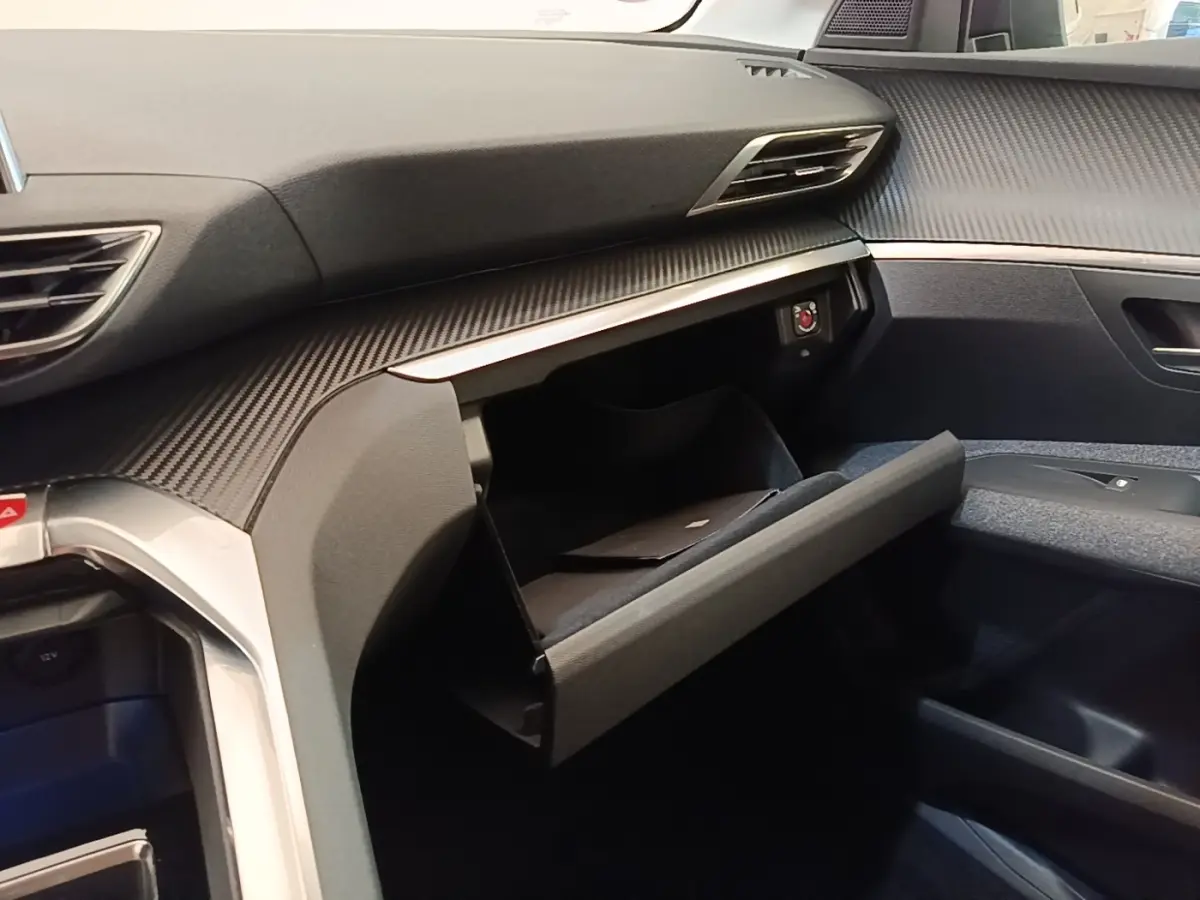 Vue intérieure côté passager du Peugeot 3008 2022 noir, avec boîte à gants ouverte et tableau de bord texturé.