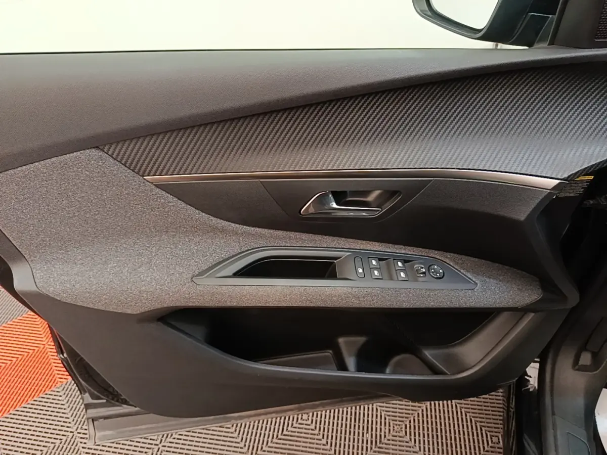 Vue intérieure du panneau de porte conducteur gris et noir du Peugeot 3008 2022 avec commandes des vitres et rétroviseurs.