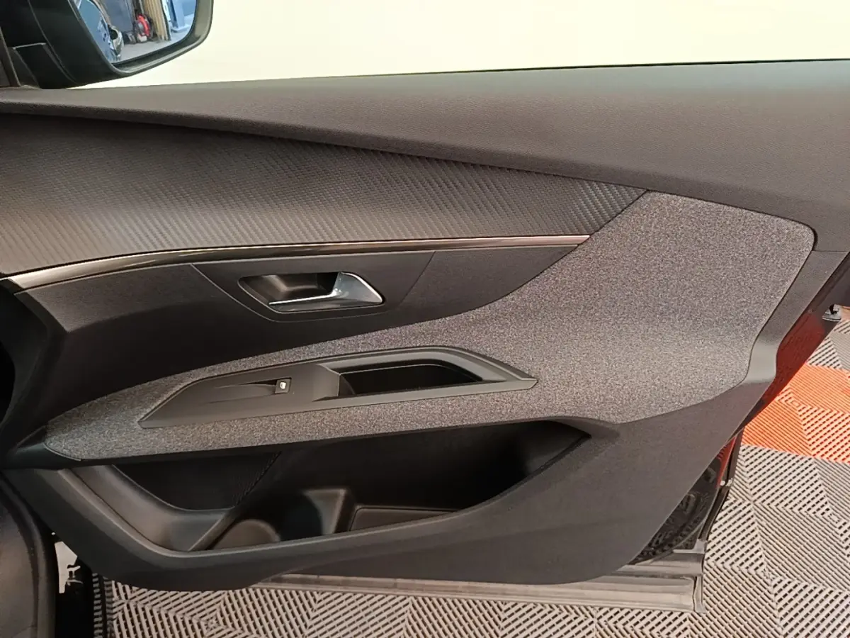 Vue intérieure du panneau de porte côté conducteur du Peugeot 3008 noir, avec habillage tissu et plastique noir.
