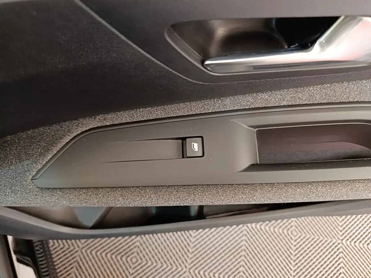 Détail de la commande d'ouverture de coffre sur la porte intérieure d'un Peugeot 3008 noir, vue rapprochée.