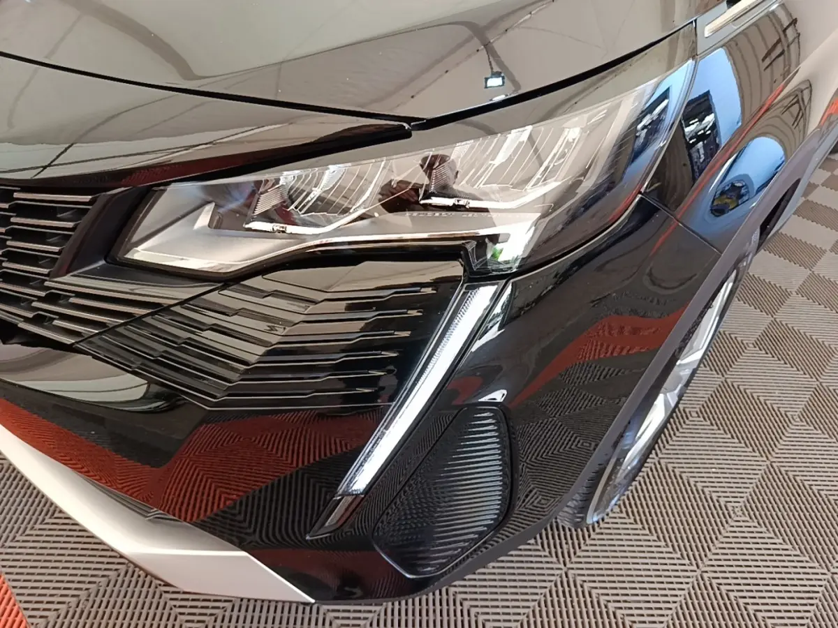 Gros plan sur l'avant droit noir brillant du Peugeot 3008 avec phare LED et calandre distinctive.