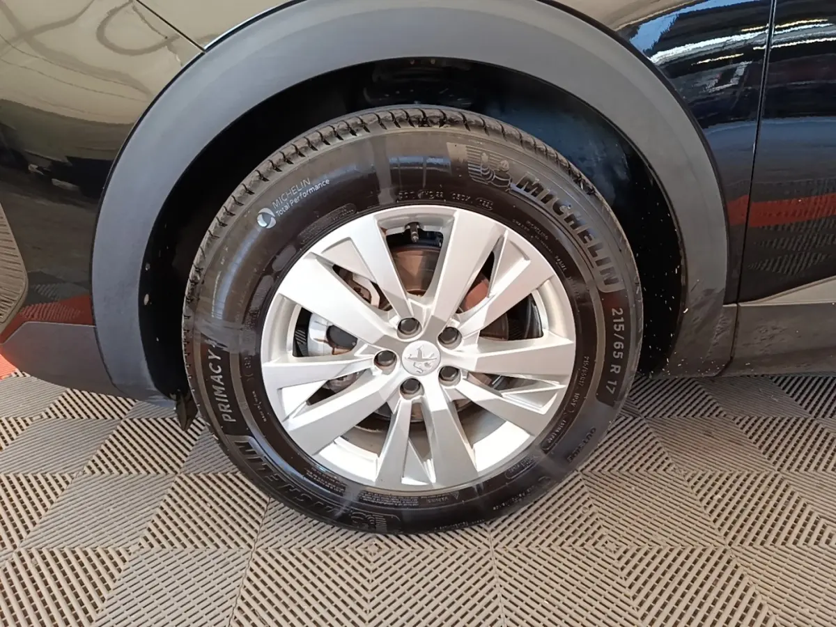 Gros plan sur la roue arrière droite d’un Peugeot 3008 noir, avec jante alliage argent et pneu Michelin.