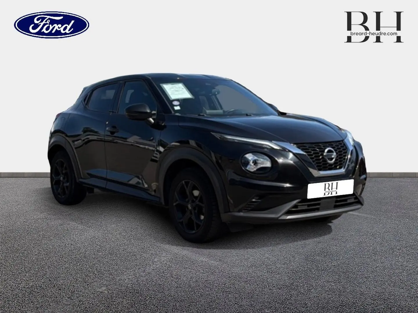 Nissan Juke noir métallisé vu en 3/4 avant droit, avec jantes noires et calandre distinctive V-Motion.