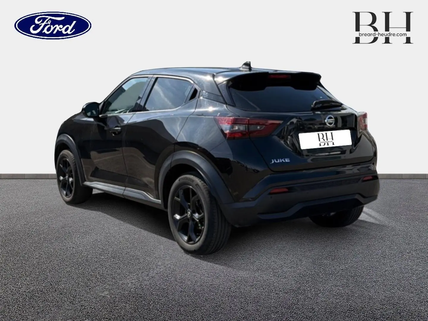Vue 3/4 arrière d’un Nissan Juke noir métallisé avec jantes noires et vitres teintées sur un sol gris.