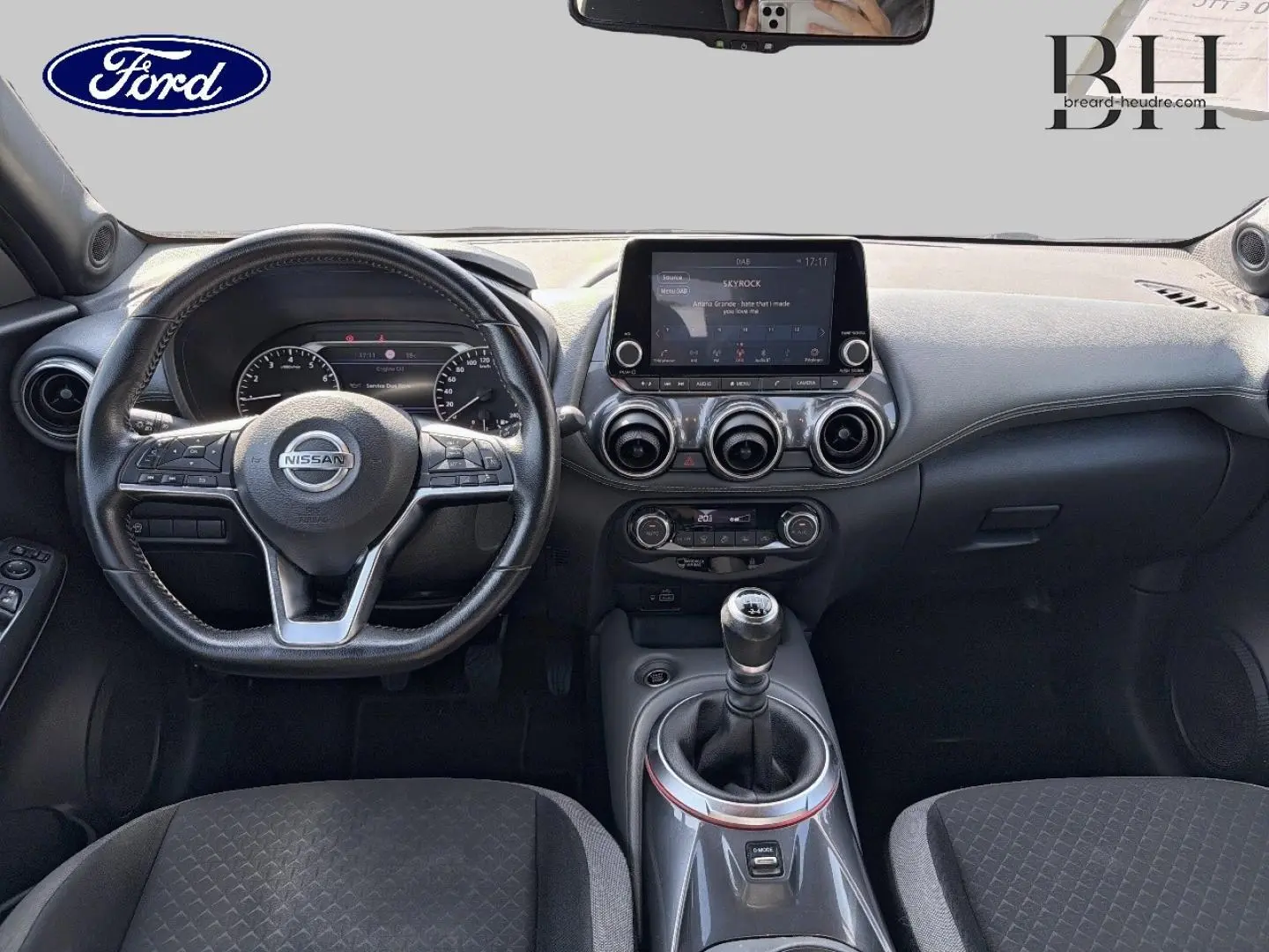 Vue intérieure avant du Nissan Juke 2020, tableau de bord noir avec écran tactile et levier de vitesse manuel.