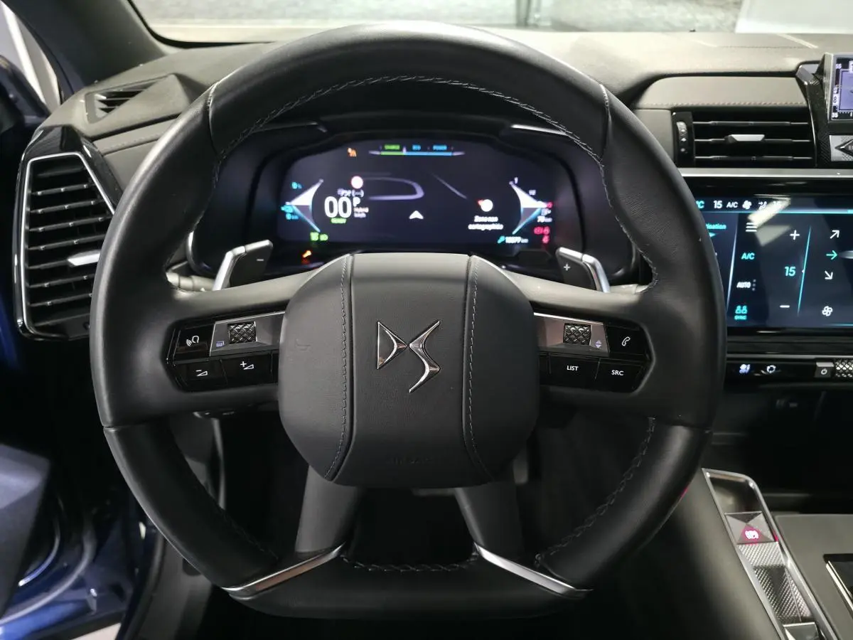 Vue rapprochée du volant en cuir noir du DS7 Crossback 2024 avec commandes intégrées et tableau de bord numérique.
