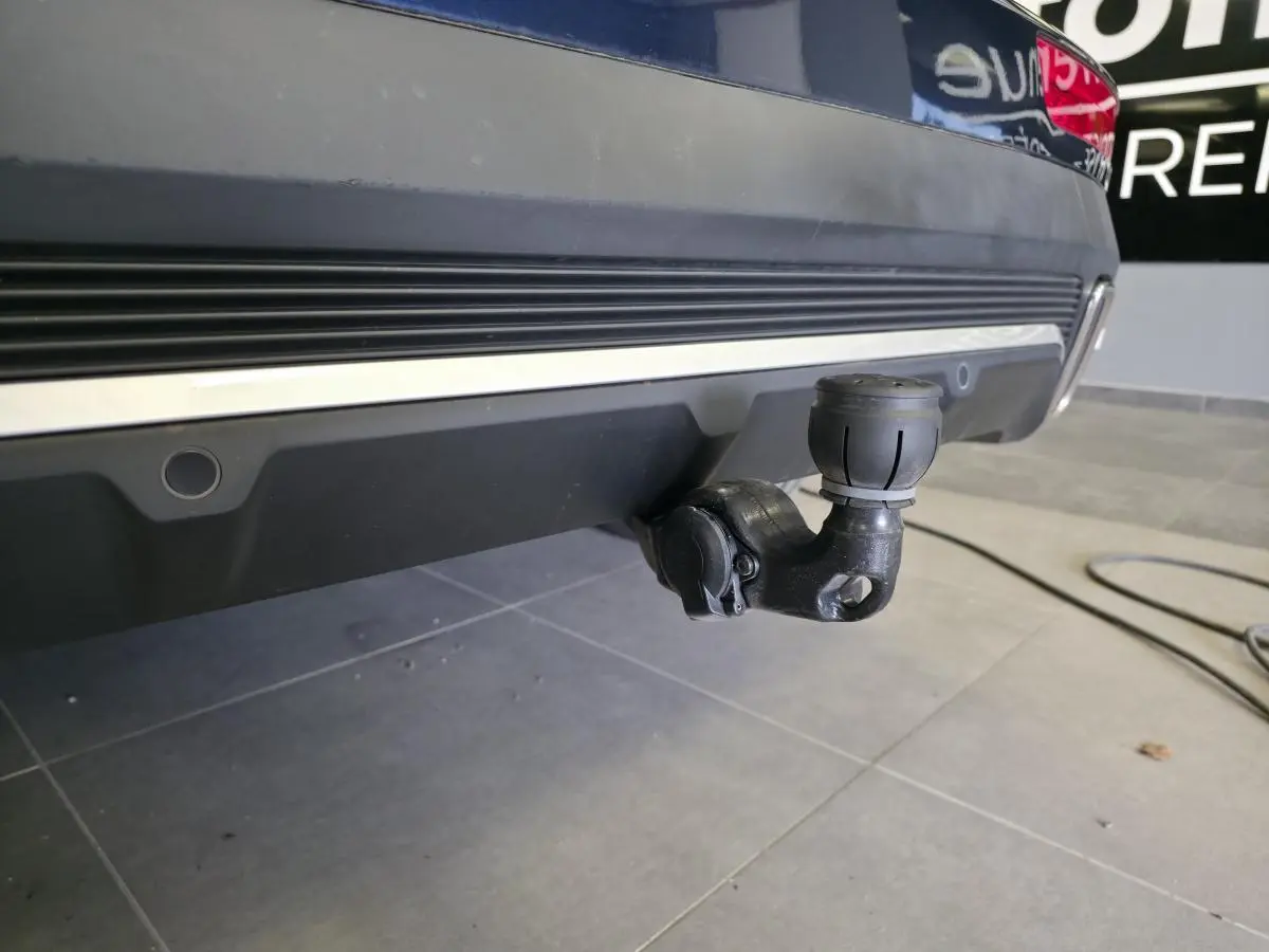 Gros plan sur l'attelage escamotable noir sous le pare-chocs arrière bleu métallisé du DS7 Crossback 2024.