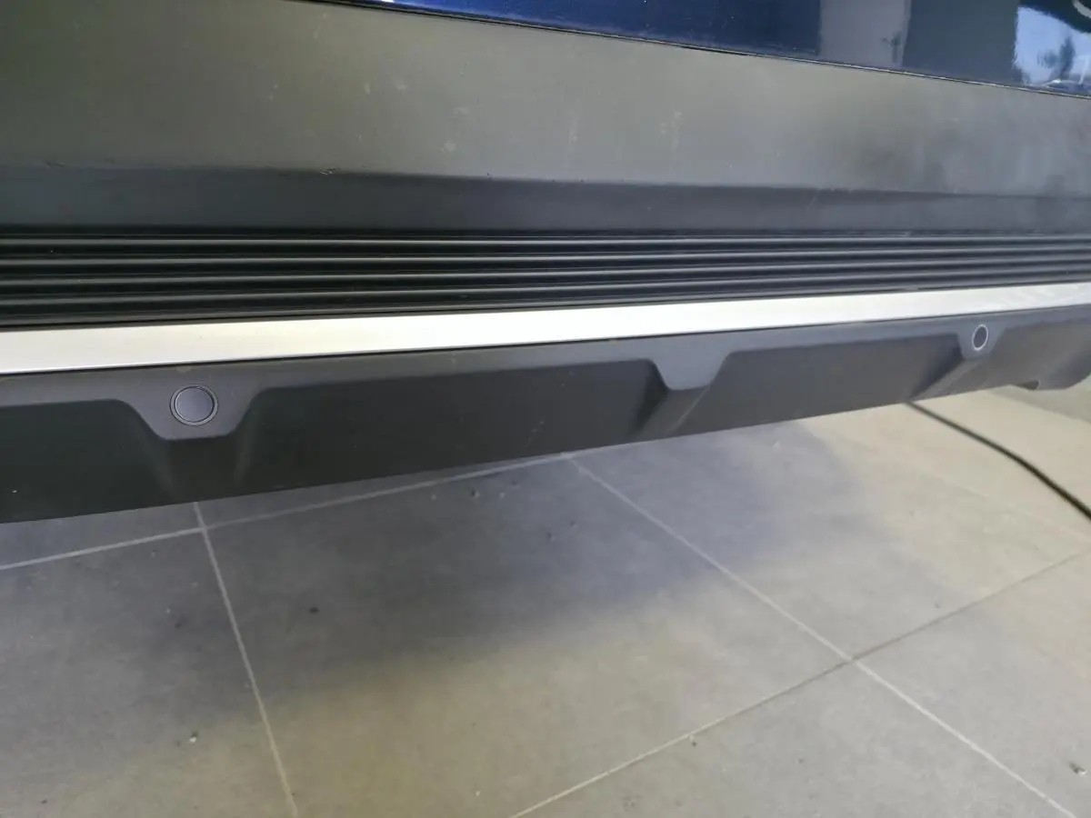 Gros plan sur le bas de caisse arrière noir et chrome du DS7 Crossback Bleu, montrant les capteurs de stationnement intégrés.