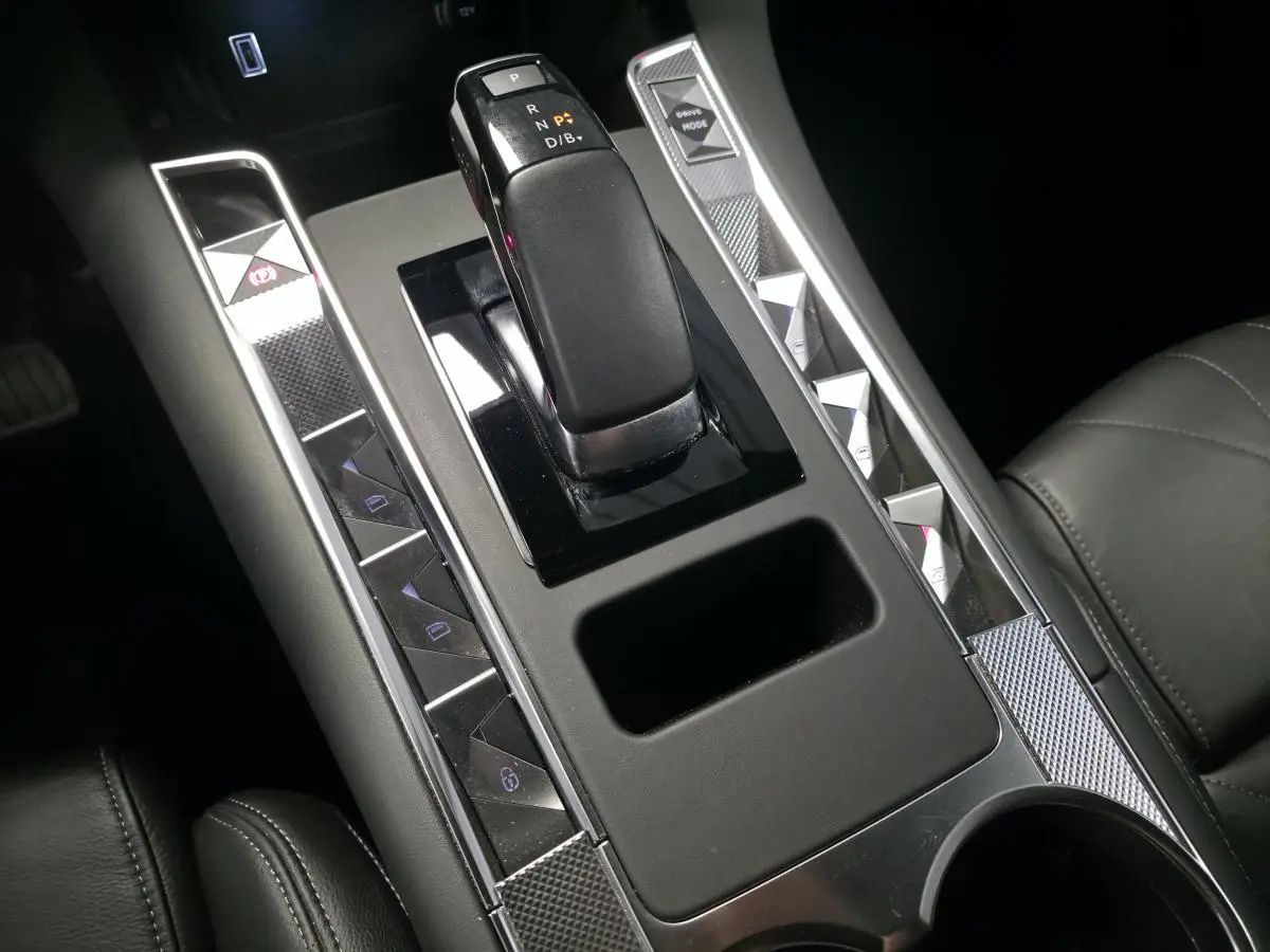 Vue rapprochée de la console centrale noire du DS7 Crossback 2024 avec levier de boîte auto et boutons argentés.