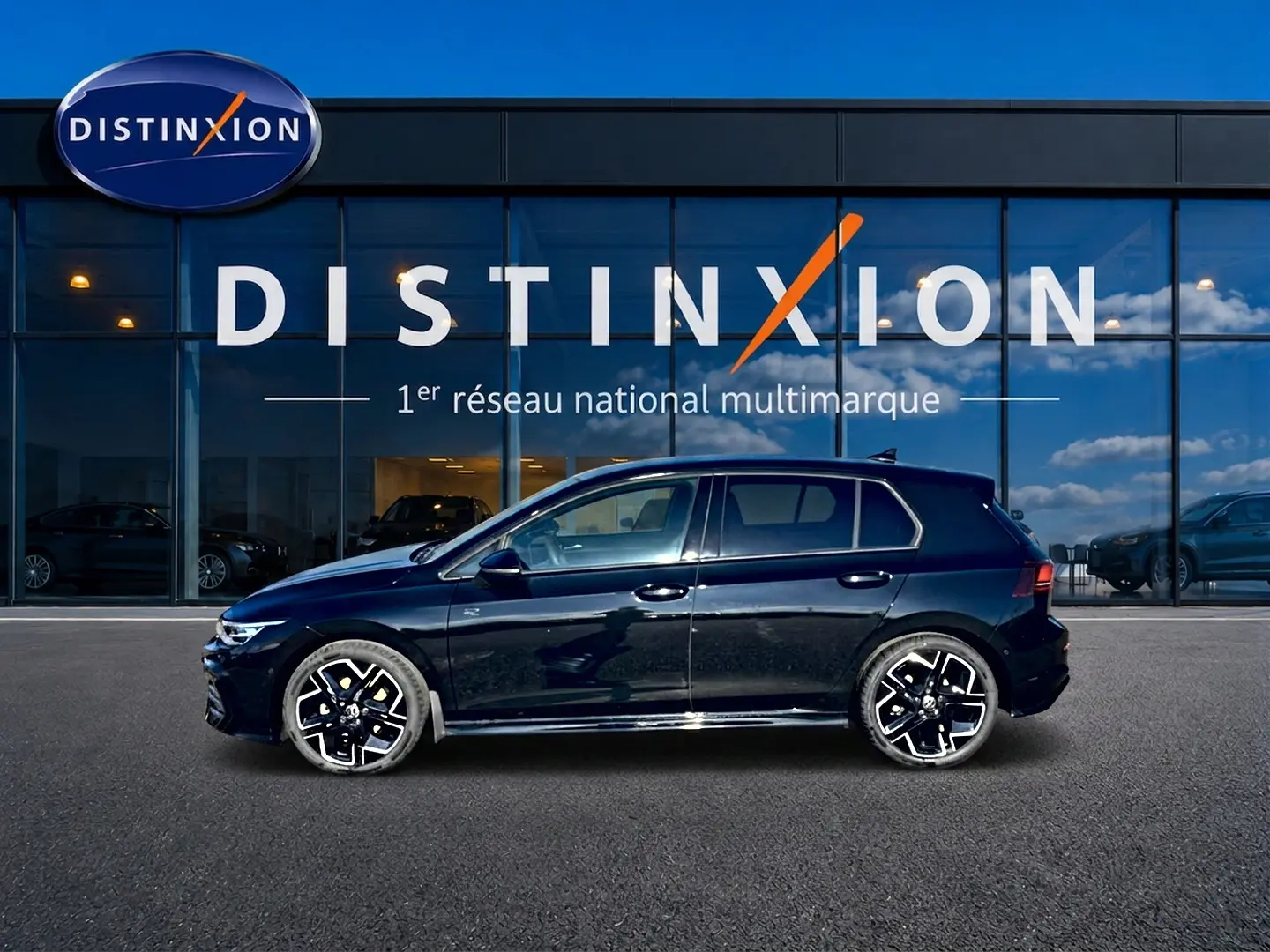 Profil droit d'une Volkswagen Golf noire 2026 R-Line avec jantes sport devant une vitrine Distinxion.