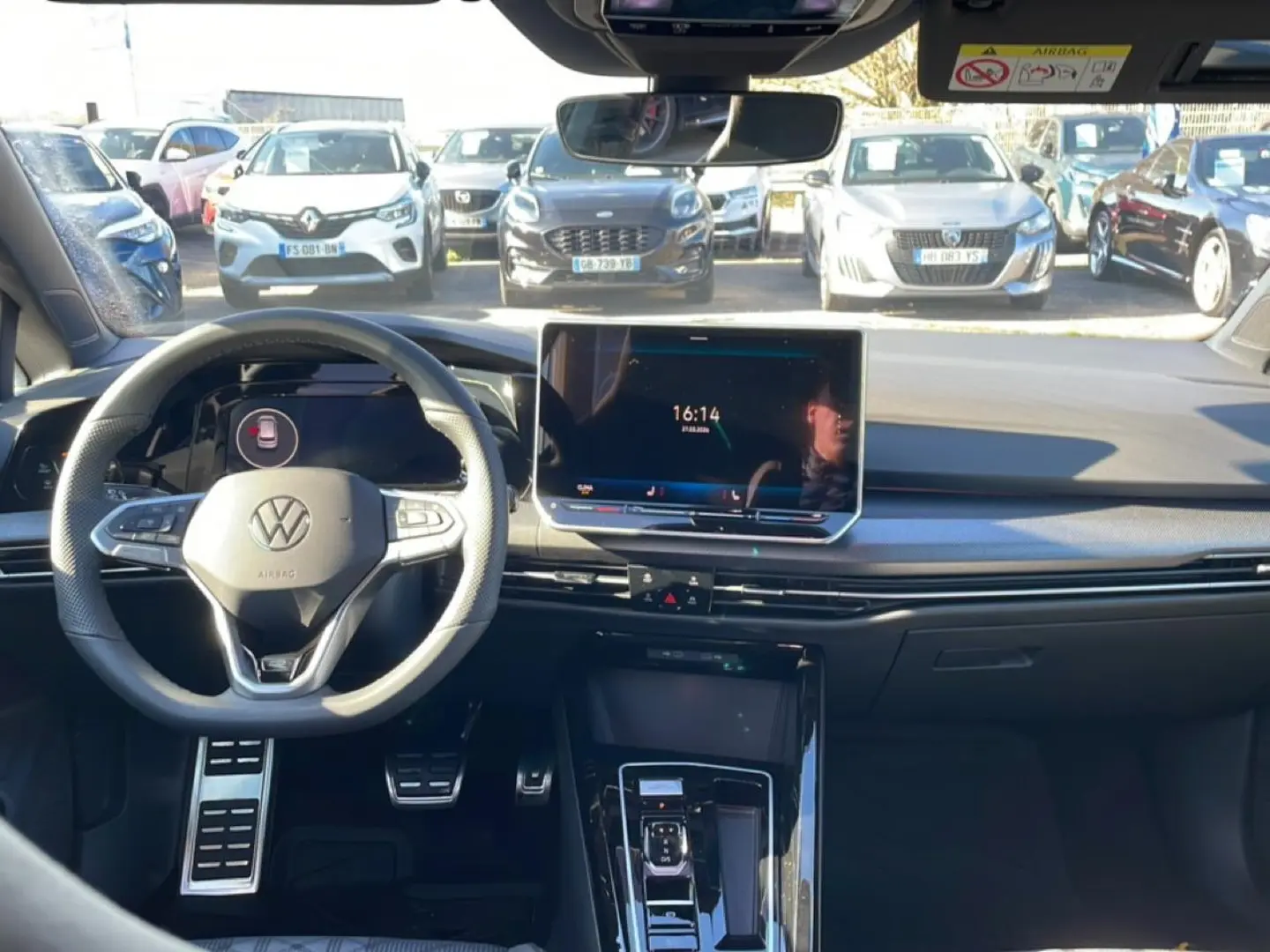 Vue intérieure avant de la Volkswagen Golf noire 2026, volant cuir multifonction et écran tactile central lumineux.