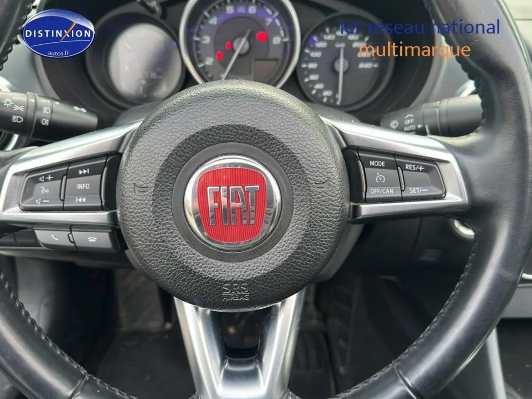 Vue rapprochée du volant cuir multifonctions noir avec logo FIAT rouge au centre du 124 Spider Lusso 2017.