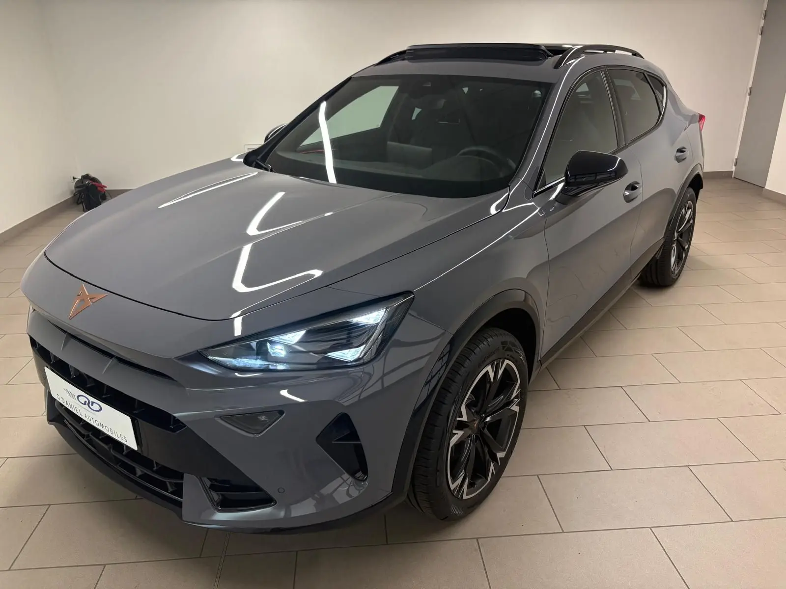 Vue 3/4 avant du CUPRA Formentor 2025 gris graphène avec toit ouvrant panoramique et jantes alliage 18'' usinées.