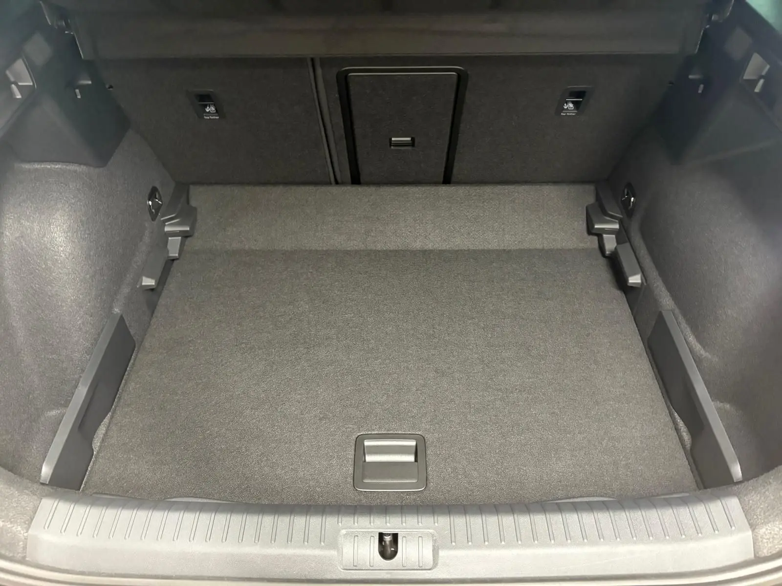 Coffre spacieux et propre du CUPRA Formentor gris Graphène, vue de l'intérieur arrière avec plancher plat et rangements latéraux.