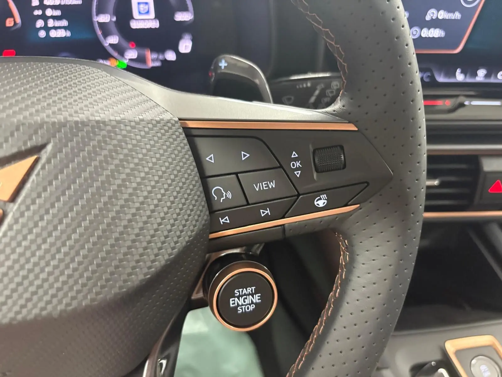 Détail du volant perforé du CUPRA Formentor 2025 avec commandes multifonctions et bouton start/stop entouré de cuivre.