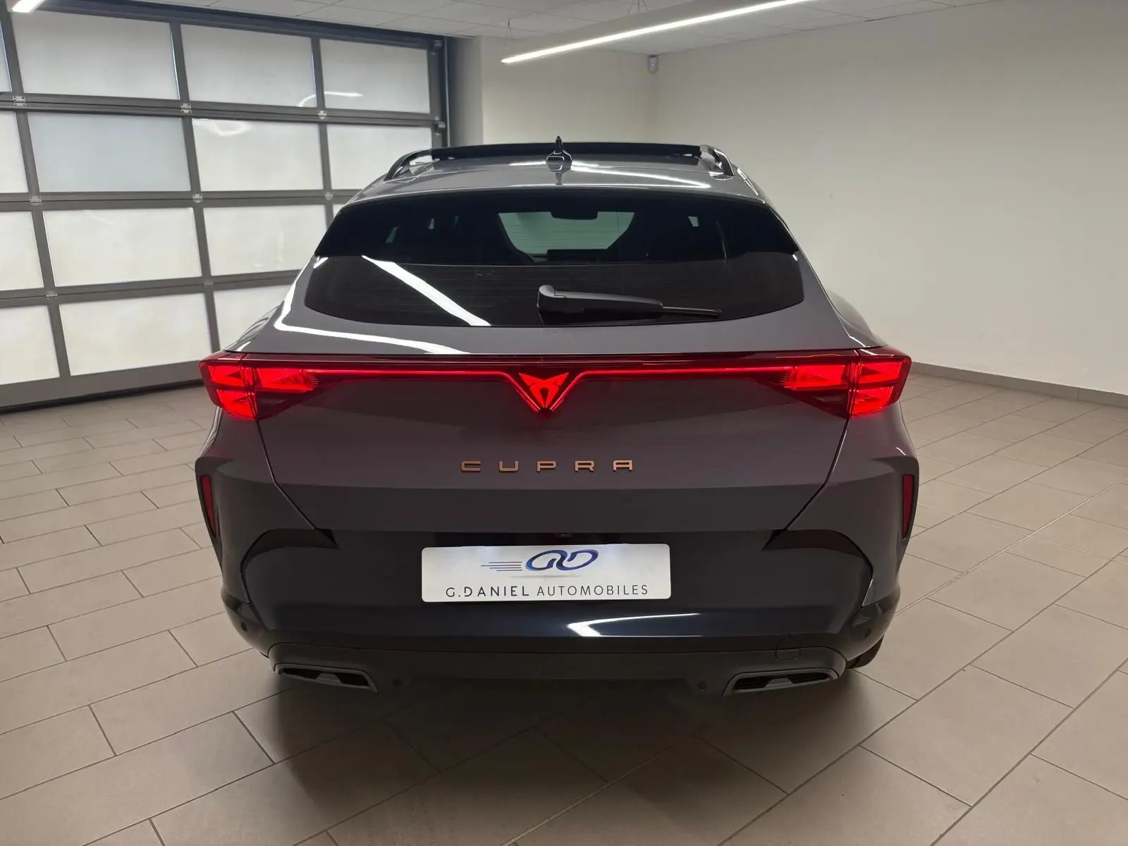 Vue arrière du CUPRA Formentor gris Graphène 2025 avec feux LED reliés et double sortie d'échappement intégrée.