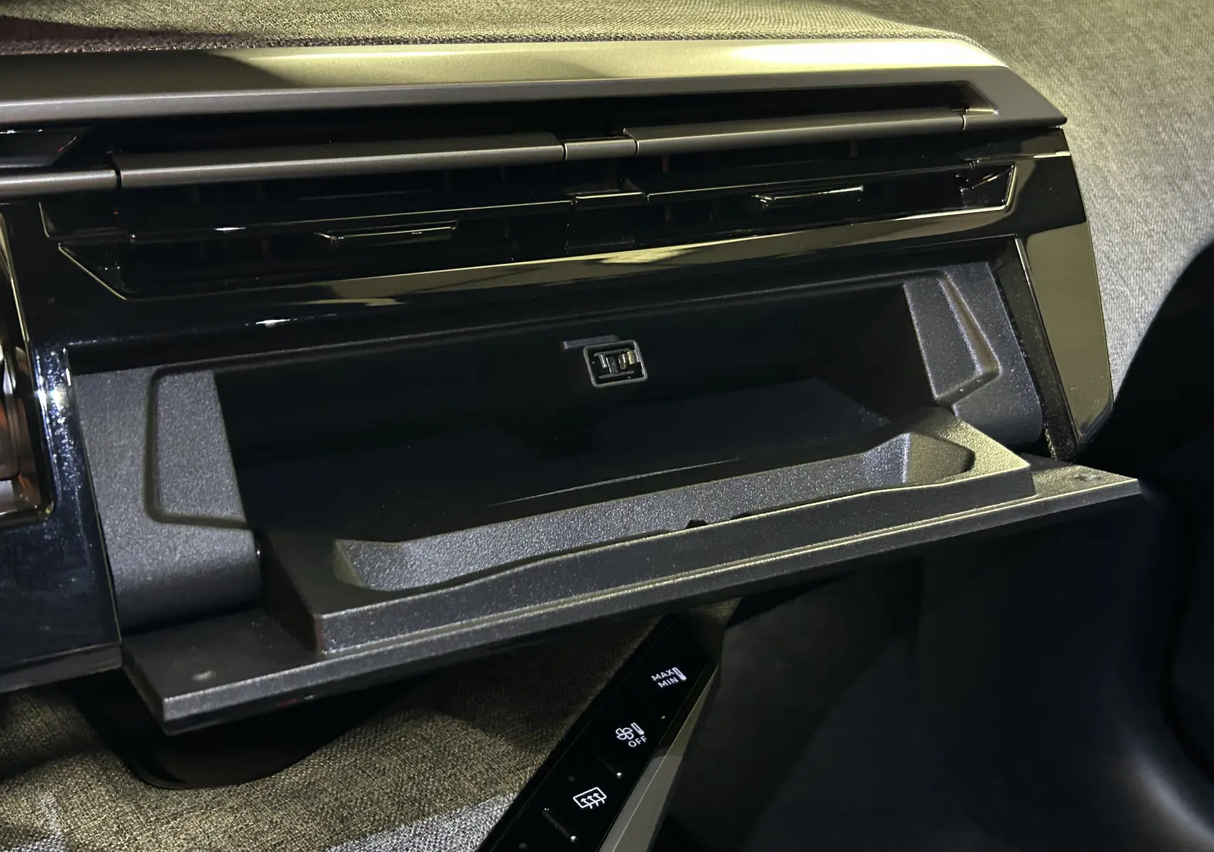 Compartiment de rangement ouvert avec prise USB sur tableau de bord noir du Peugeot 3008 Hybrid 2025 côté passager.