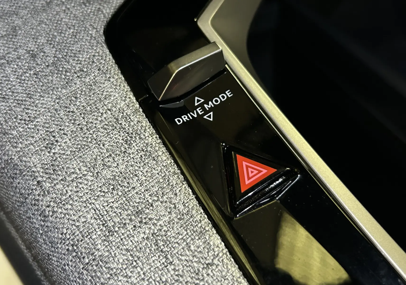 Gros plan sur le bouton Drive Mode et le triangle de signalisation d'alerte dans l'habitacle du Peugeot 3008 hybride 2025.