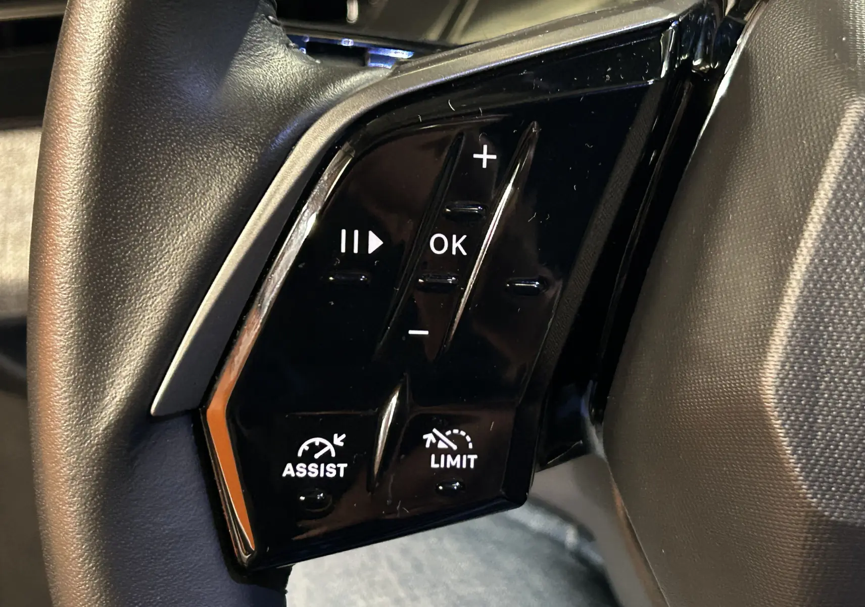 Gros plan sur les commandes noires du volant côté gauche du Peugeot 3008 Bleu Ingaro hybride 2025.
