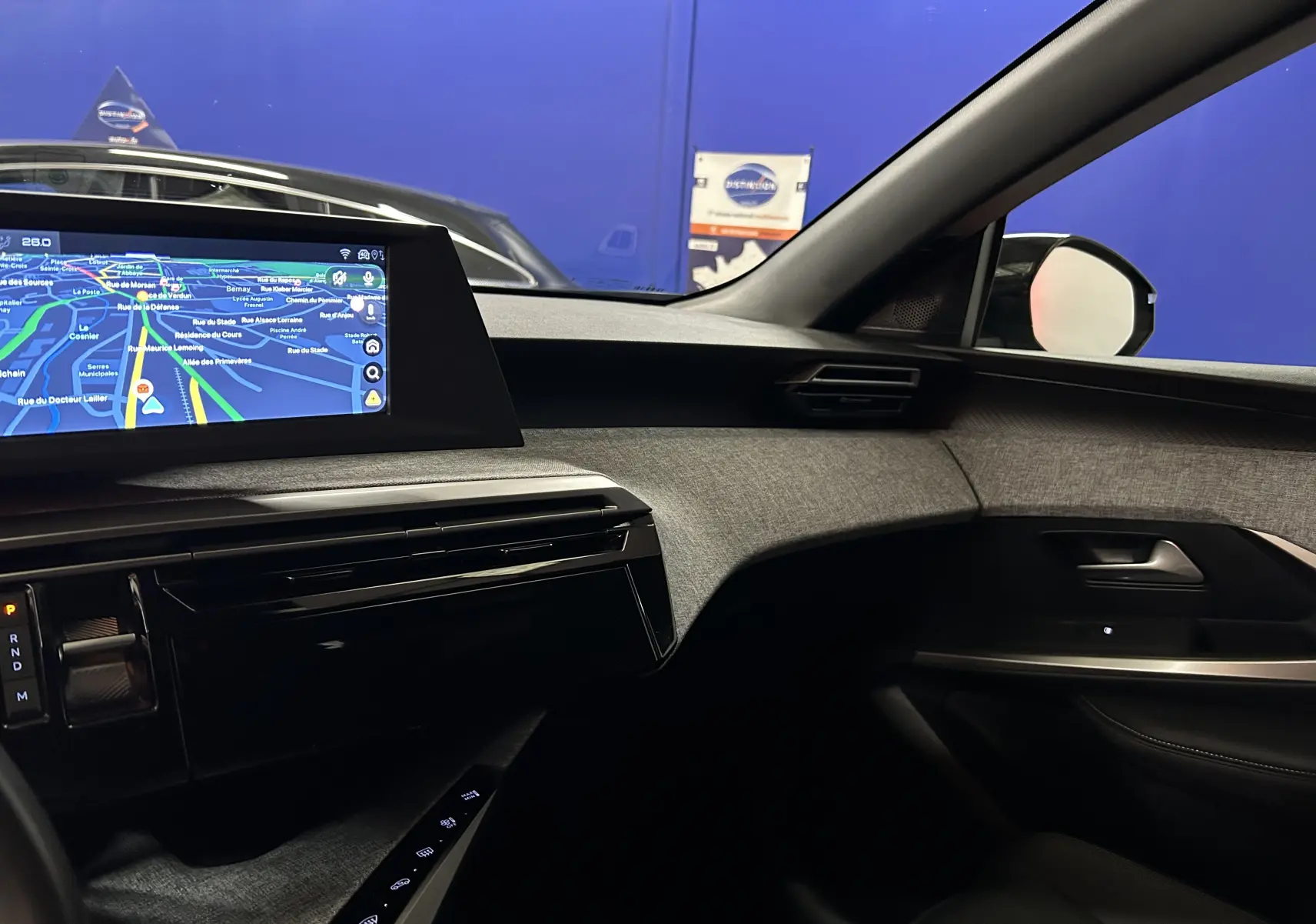 Vue intérieure côté passager du tableau de bord et écran tactile du Peugeot 3008 Hybrid 2025 avec finition tissu gris.