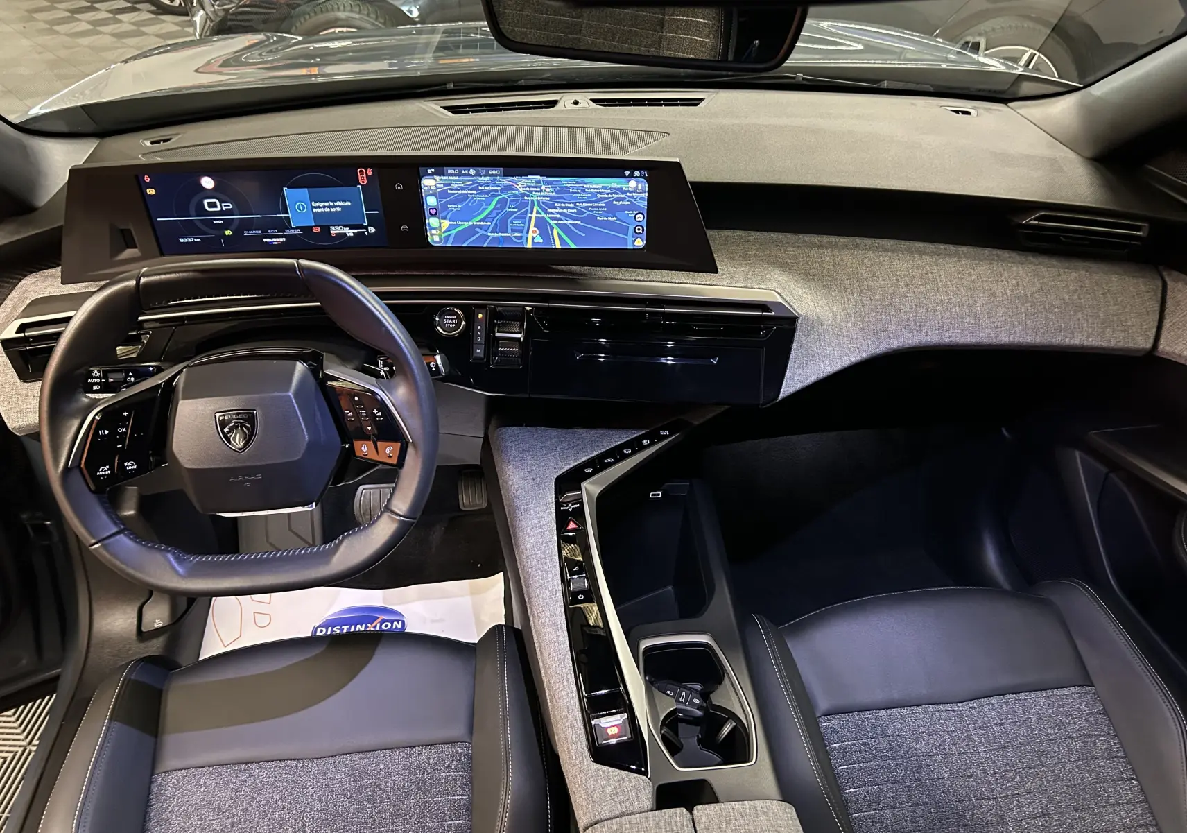 Vue intérieure du tableau de bord et volant du Peugeot 3008 III Hybrid 145 Allure en tissu gris et cuir noir avec écran tactile panoramique.