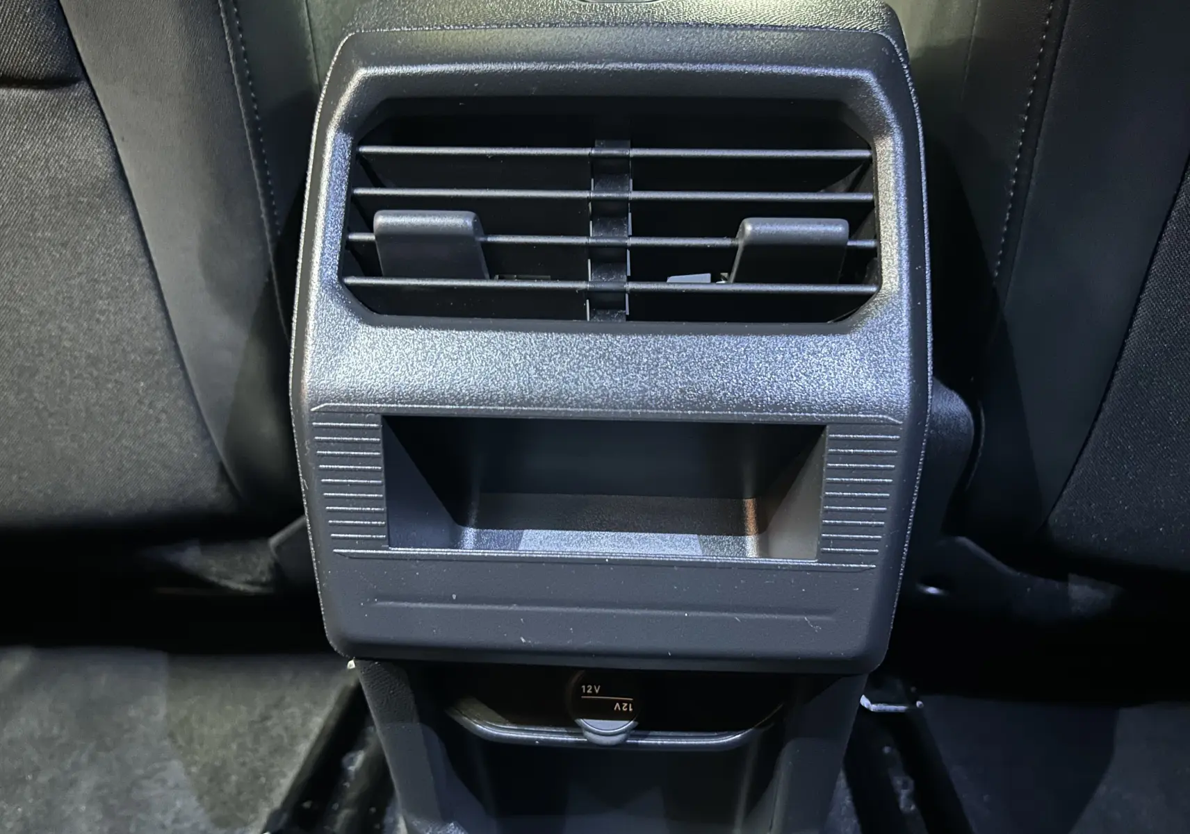 Gros plan sur la console arrière noire du Peugeot 3008 III Hybrid 145 Allure Bleu Ingaro, avec prise 12V visible.