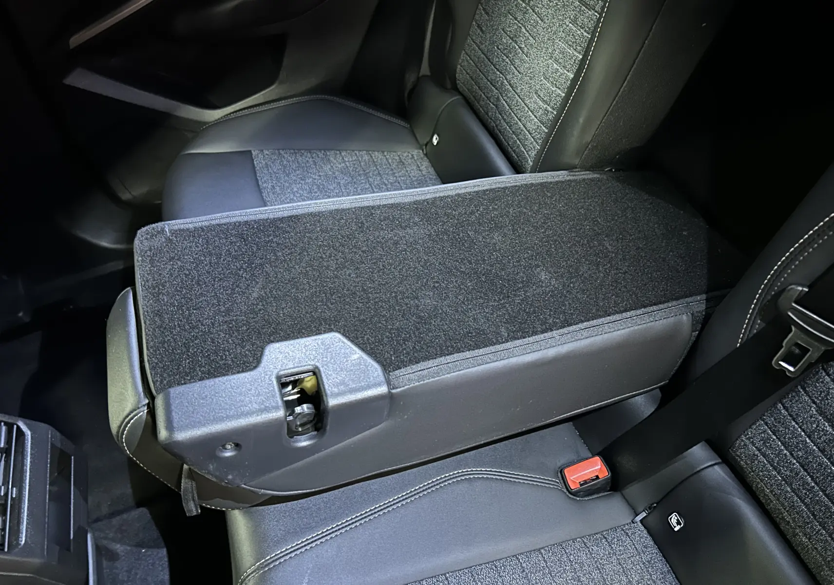 Vue rapprochée de l'accoudoir central relevé et des sièges arrière en tissu gris et cuir noir du Peugeot 3008 Bleu Ingaro.