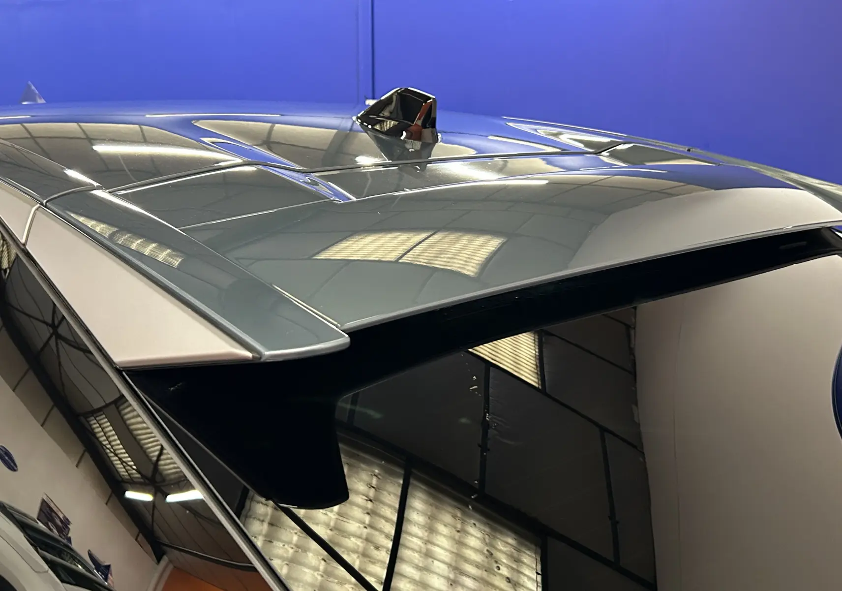 Toit panoramique et antenne requin sur le dessus arrière d'un Peugeot 3008 bleu Ingaro, vue en plongée.