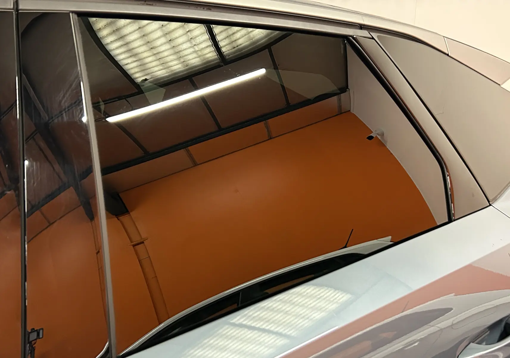 Reflet du toit vitré sur la porte côté droit d'un Peugeot 3008 Bleu Ingaro 2025 en intérieur lumineux