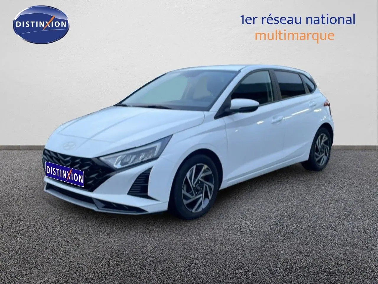 Vue 3/4 avant droite d'une Hyundai i20 blanche Atlas 2025 avec jantes alliage et calandre noire distinctive.