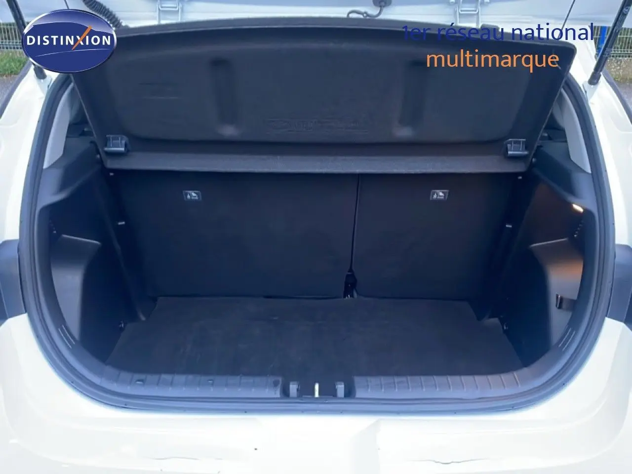 Coffre ouvert vu de l'arrière d'une Hyundai i20 blanc atlas, montrant l'espace de chargement vide et la trappe de coffre.