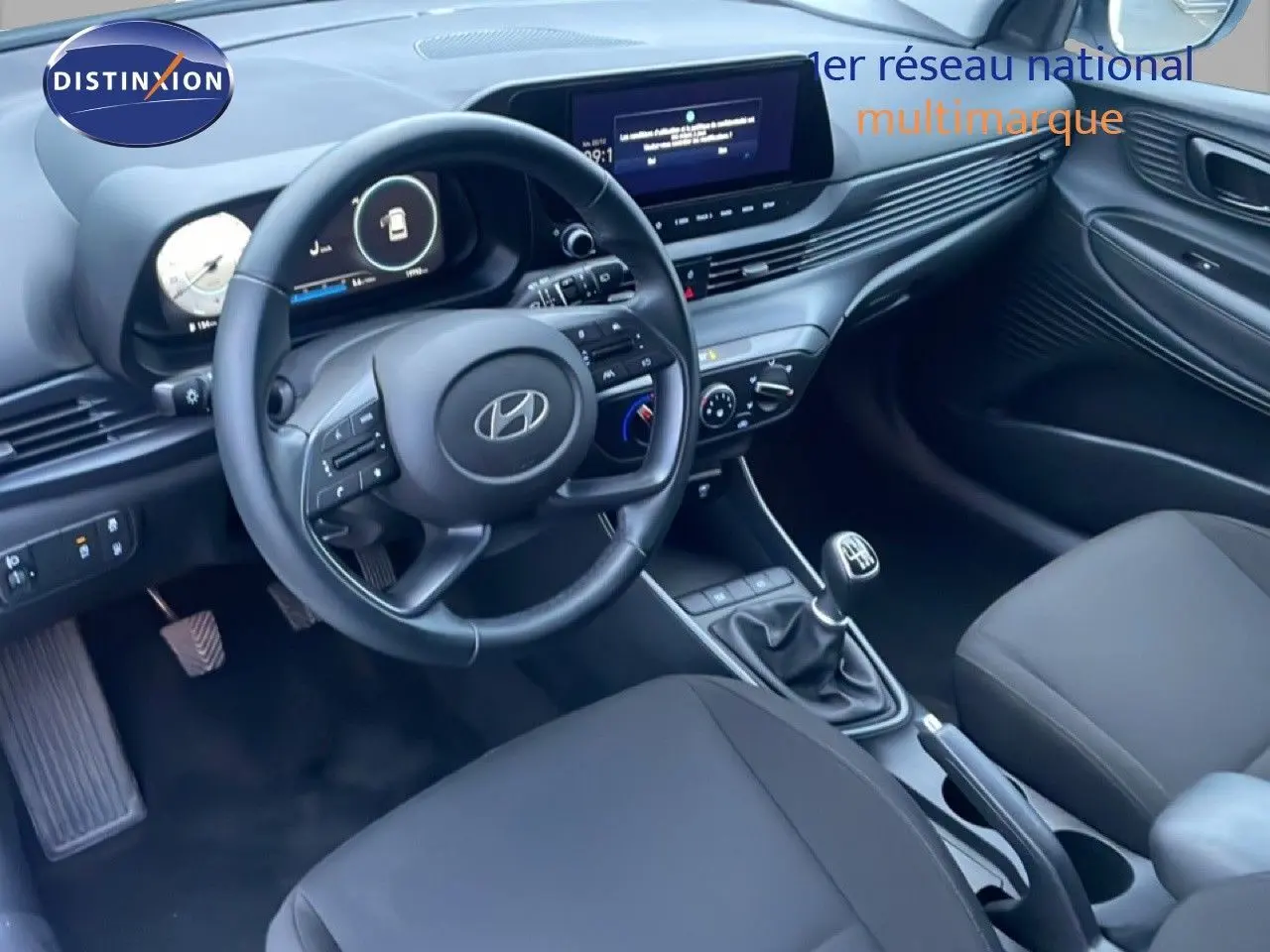 Vue intérieure côté conducteur de la Hyundai i20 2025, tableau de bord moderne avec volant cuir et écran central tactile.