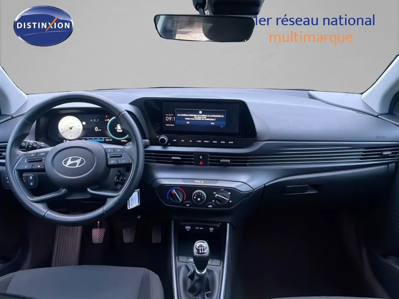 Vue intérieure avant de la Hyundai i20 blanche Atlas 2025, tableau de bord moderne avec écran tactile et boîte manuelle.