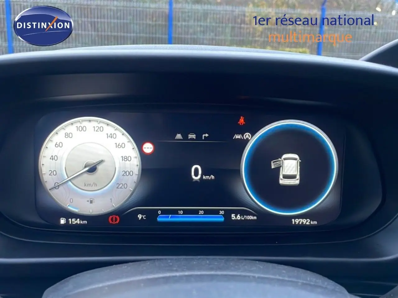 Tableau de bord numérique de la Hyundai i20 2025, affichant vitesse, consommation et porte ouverte, vue frontale rapprochée.