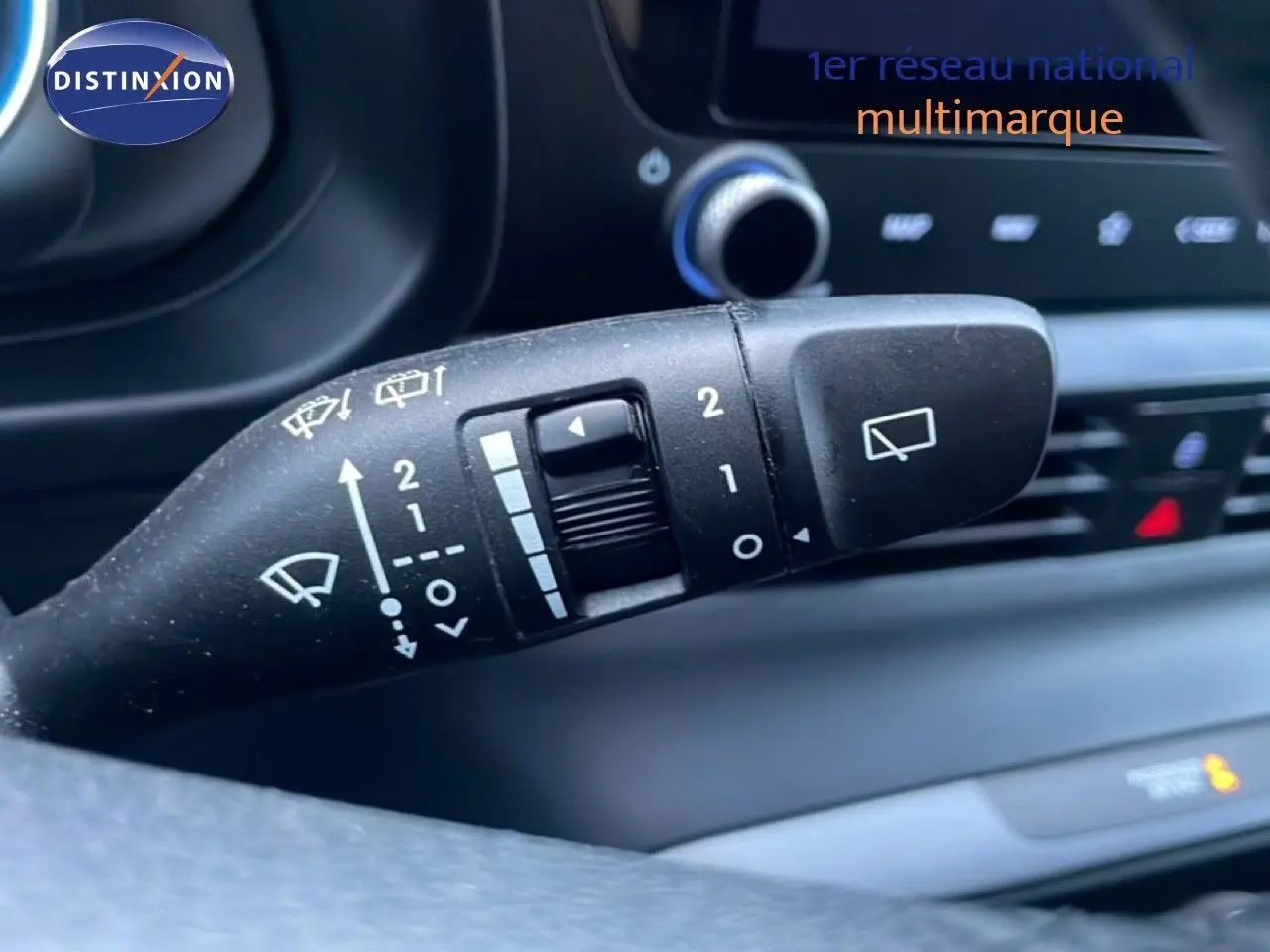 Gros plan sur la commande d’essuie-glace à gauche du volant dans l’habitacle d’une Hyundai i20 blanc Atlas 2025.